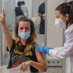 Una joven sonríe y saluda mientras recibe la vacuna contra el Covid-19 en el dispositivo puesto en marcha en la Ciutat de les Arts i les Ciències de Valencia