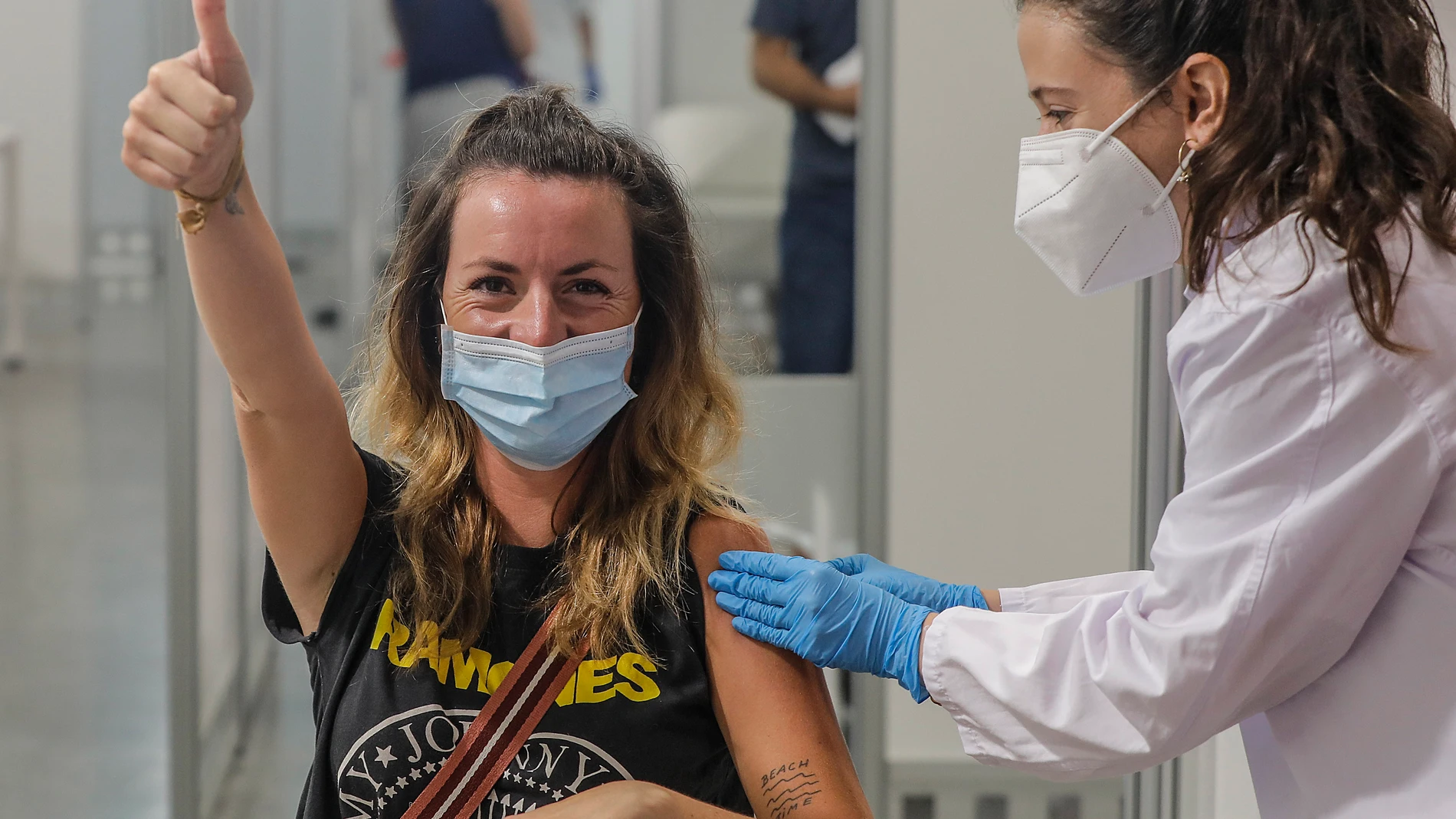 Una joven sonríe y saluda mientras recibe la vacuna contra el Covid-19 en el dispositivo puesto en marcha en la Ciutat de les Arts i les Ciències de Valencia