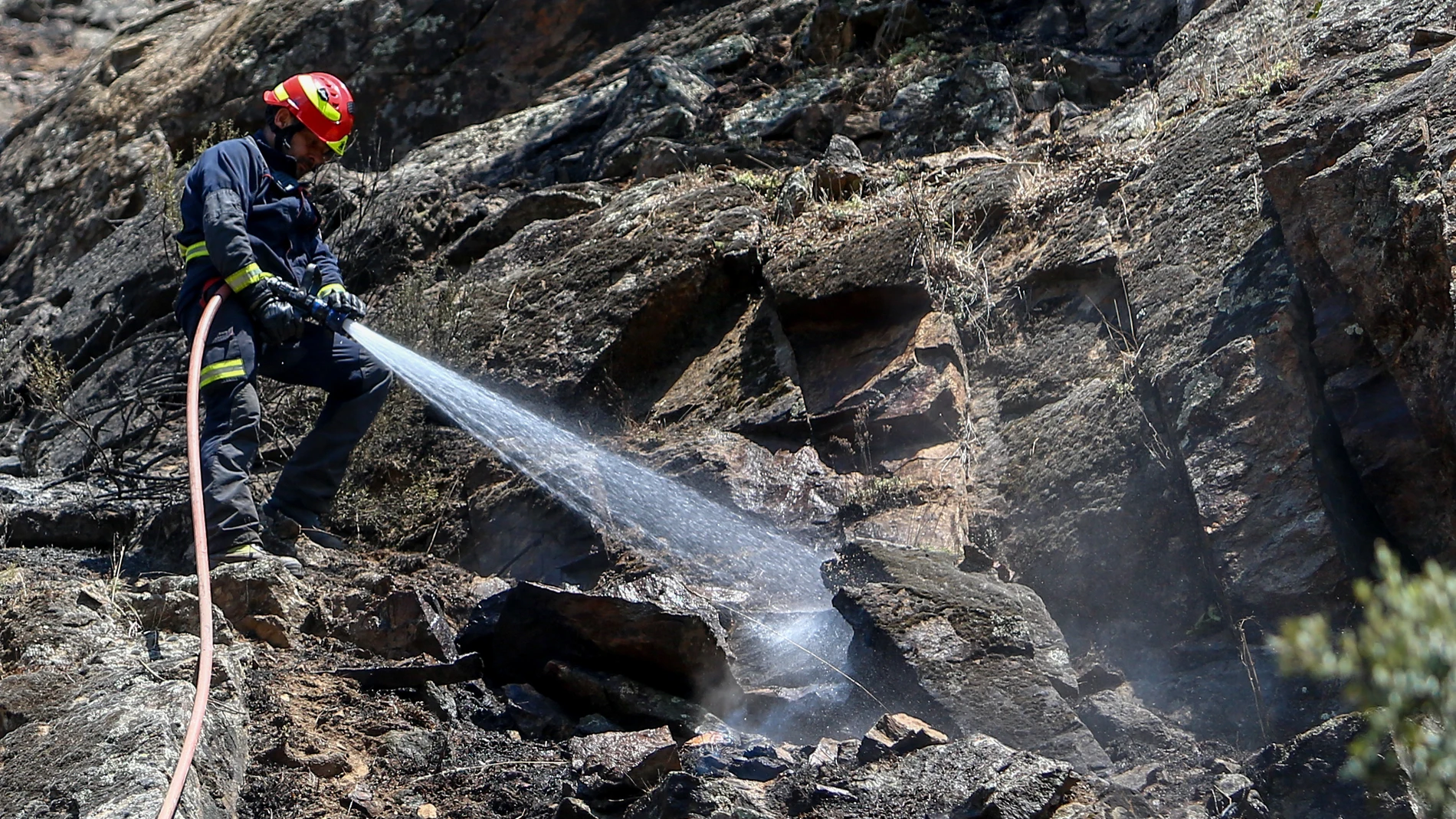 Un bombero trabaja en la extinción de un foco de fuego en el incendio del pantano de San Juan
