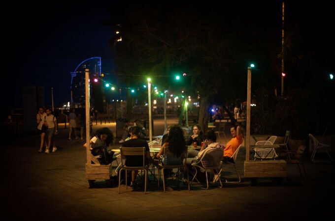 Varias personas en la terraza de un bar, frente a la playa de la Barceloneta