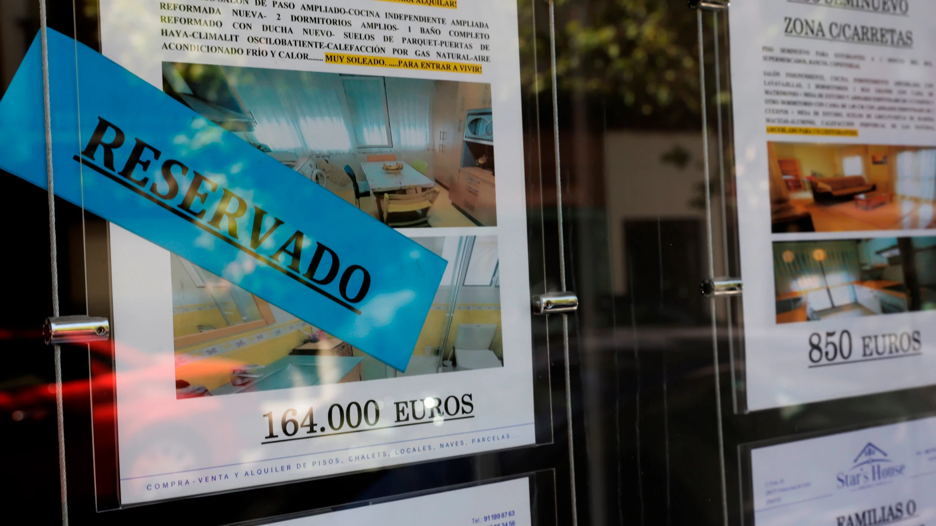 Anuncios de pisos y casas en venta y alquiler en el escaparate de una inmobiliaria, en Madrid