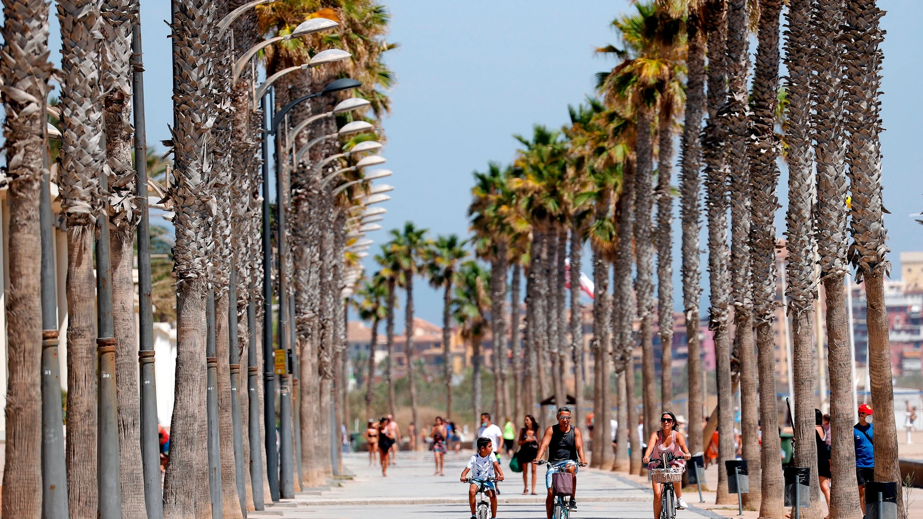 Varias personas pasean en bicicleta por el paseo de la playa de La Patacona De Alboraya (Valencia)