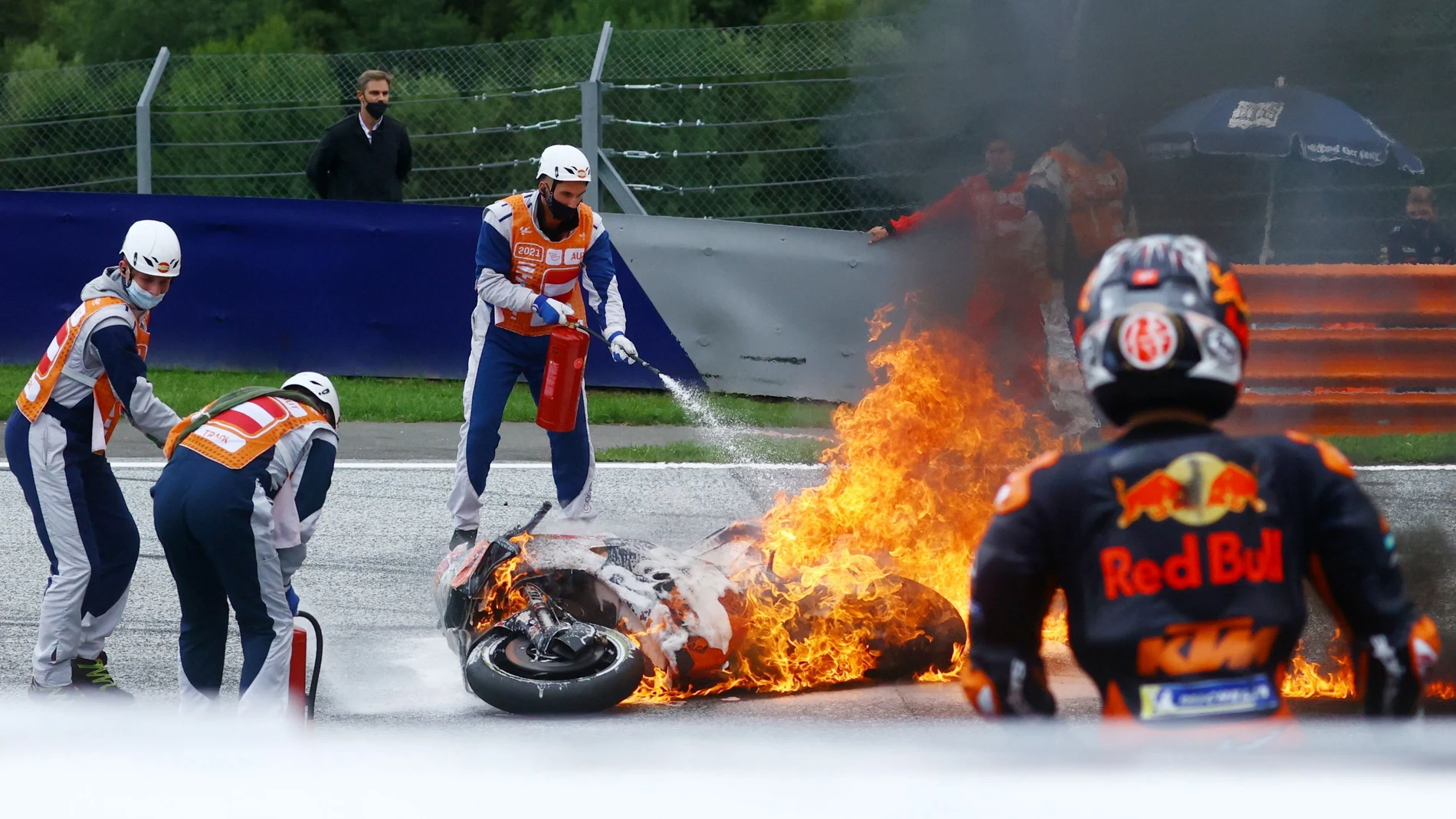 Los comisarios tratan de apagar las motos de Pedrosa y Savadori, que se incendieron en el accidente entre ambos en el Red Bull Ring de Spielberg