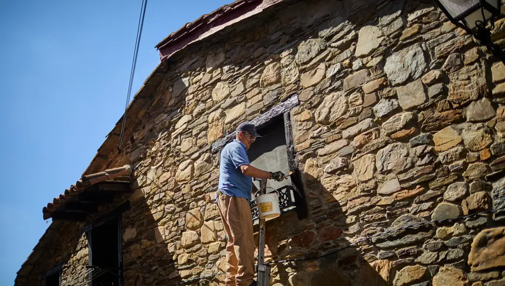 Un vecino arregla la fachada de su vivienda en Puebla de la Sierra, a 110 km del Madrid capital
