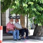 Un par de jubilados se resguardan del calor bajo un árbol