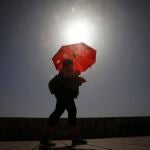 Una mujer camina resguardándose del sol con una sombrilla. EFE/Salas