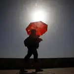 Una mujer camina resguardándose del sol con una sombrilla. EFE/Salas