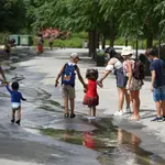 Varios niños pasan por un arroyo de agua en el Parc Central (Valencia)