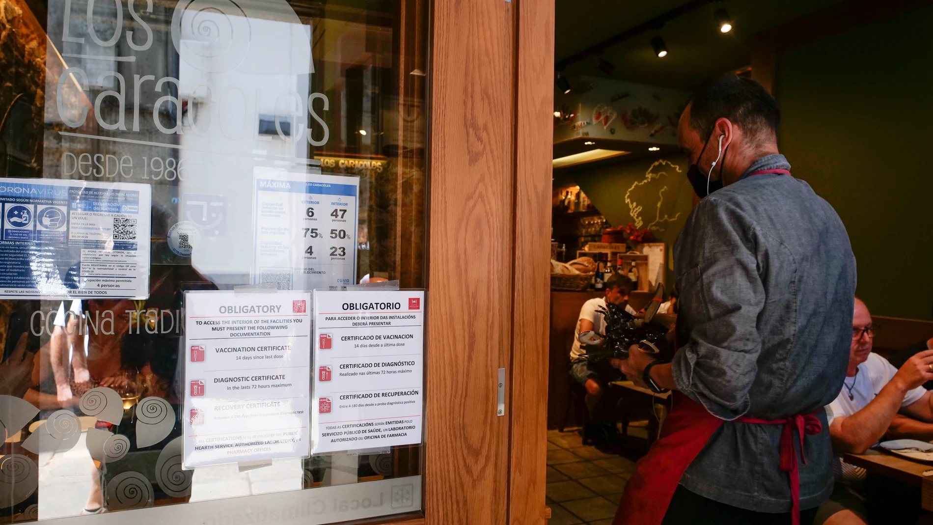 Carteles de indicaciones de obligatoriedad de presentar el certificado antes de acceder al interior de una Marisquería de la Rua da Raiña en Santiago de Compostela (La Coruña, Galicia)