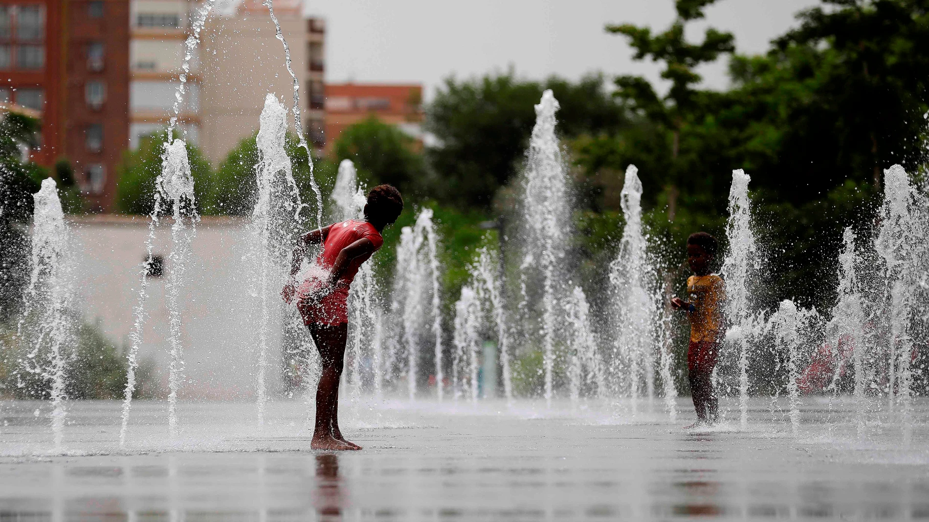 Dos niños se refrescan en una fuente de la ciudad de Valencia