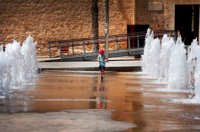 Un niño patina entre chorros de agua en una fuente en Elche (Alicante) para mitigar las altas temperaturas debido a la ola de calor que azota la península