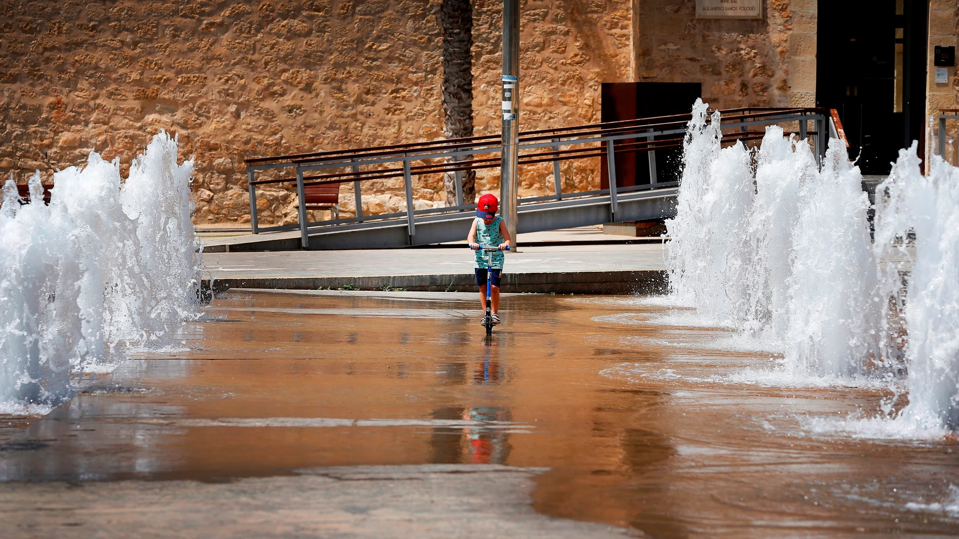 Un niño patina entre chorros de agua en una fuente en Elche (Alicante) para mitigar las altas temperaturas debido a la ola de calor que azota la península