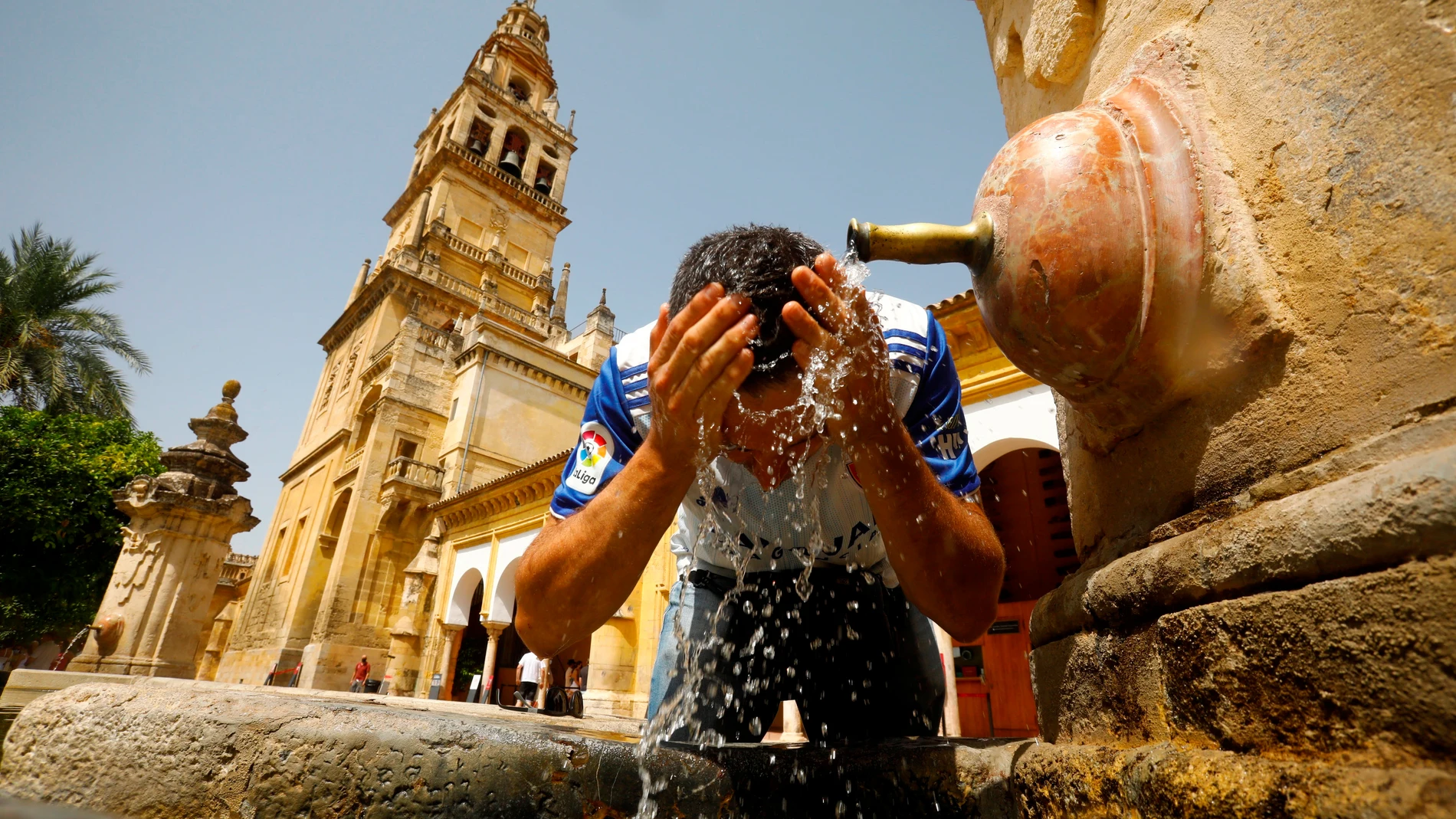 Un turista se refresca en el Patio de los Naranjos de Córdoba, ciudad en la que se superaron los 46 grados durante el sábado