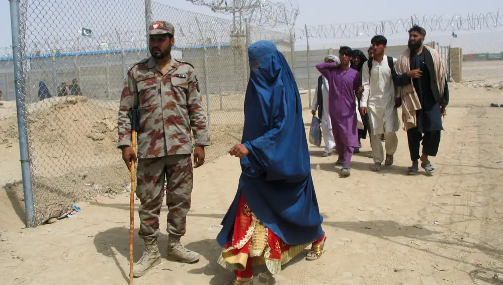 Una mujer con burqa cruza el paso fronterizo para entrar en Pakistán ayer ante la mirada de un soldado