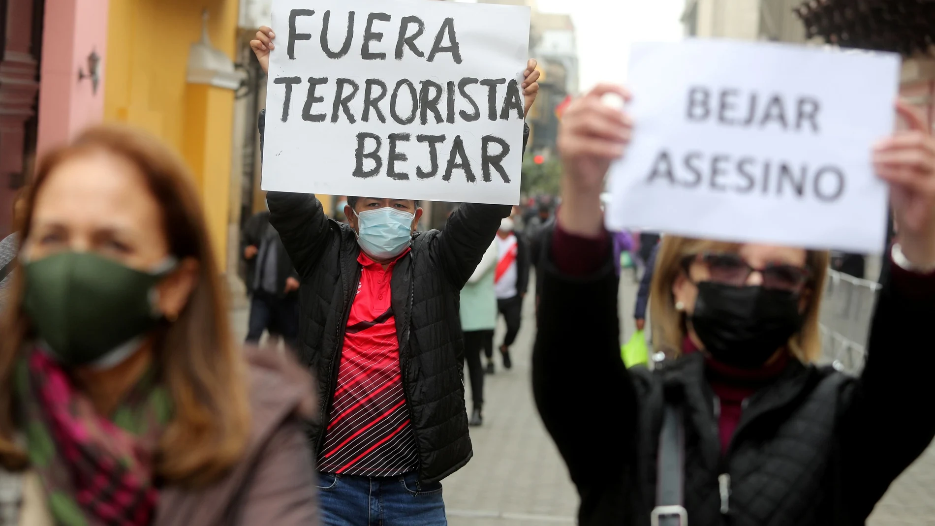 A man holds a sign reading "Terrorist Bejar out" during a protest against Peru's Foreign Minister Hector Bejar who resigned amid outrage over remarks he made before taking office about a rebel group that killed tens of thousands of people, in Lima, Peru August 17, 2021. The other sign reads "Bejar assessin." REUTERS/Sebastian Castaneda