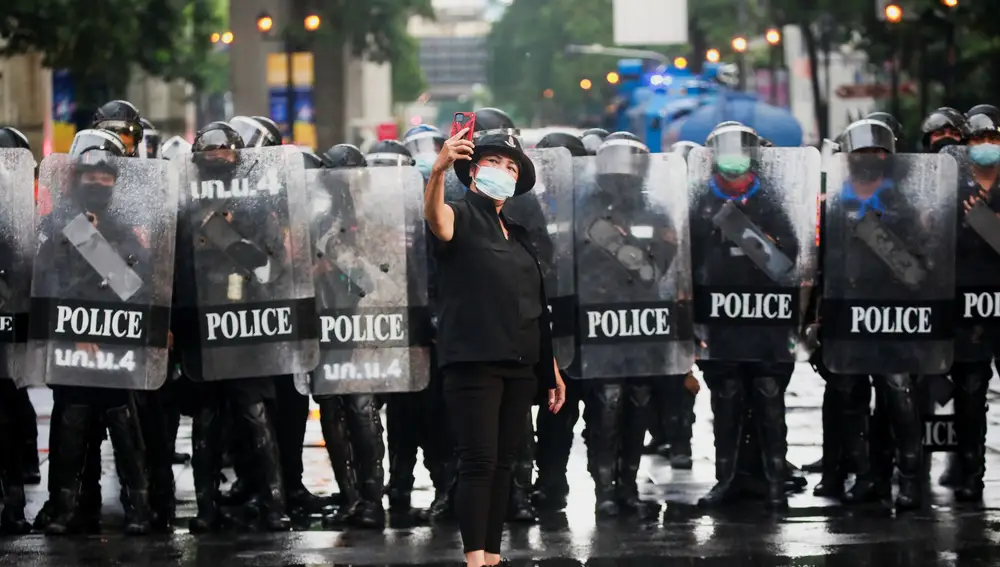 Una mujer se fotografía delante de la Policía en una manifestación en Bangkok
