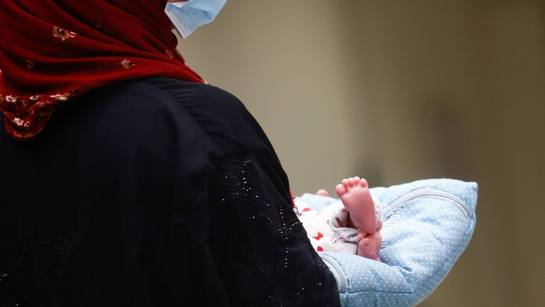 Una mujer sostiene a un bebé afgano evacuado en el aeropuerto de Roma