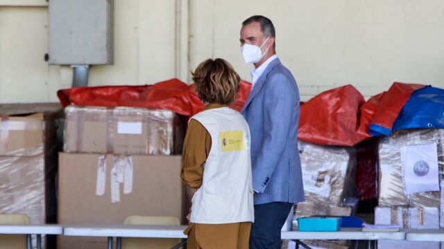 El Rey Felipe VI conversa con una cooperante a su llegada al hangar para visitar el dispositivo provisional en Torrejón de Ardoz