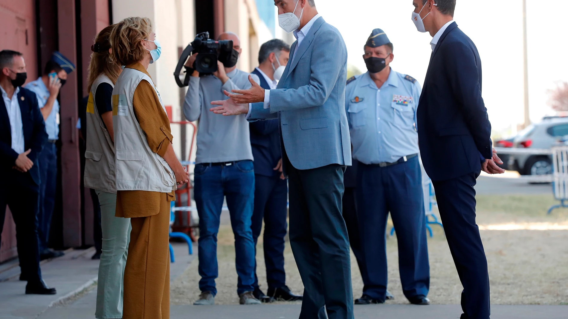 El rey Felipe VI y el presidente del Gobierno, Pedro Sánchez, conversan con varias personas durante su visita al centro de acogida temporal instalado en la base de Torrejón de Ardoz