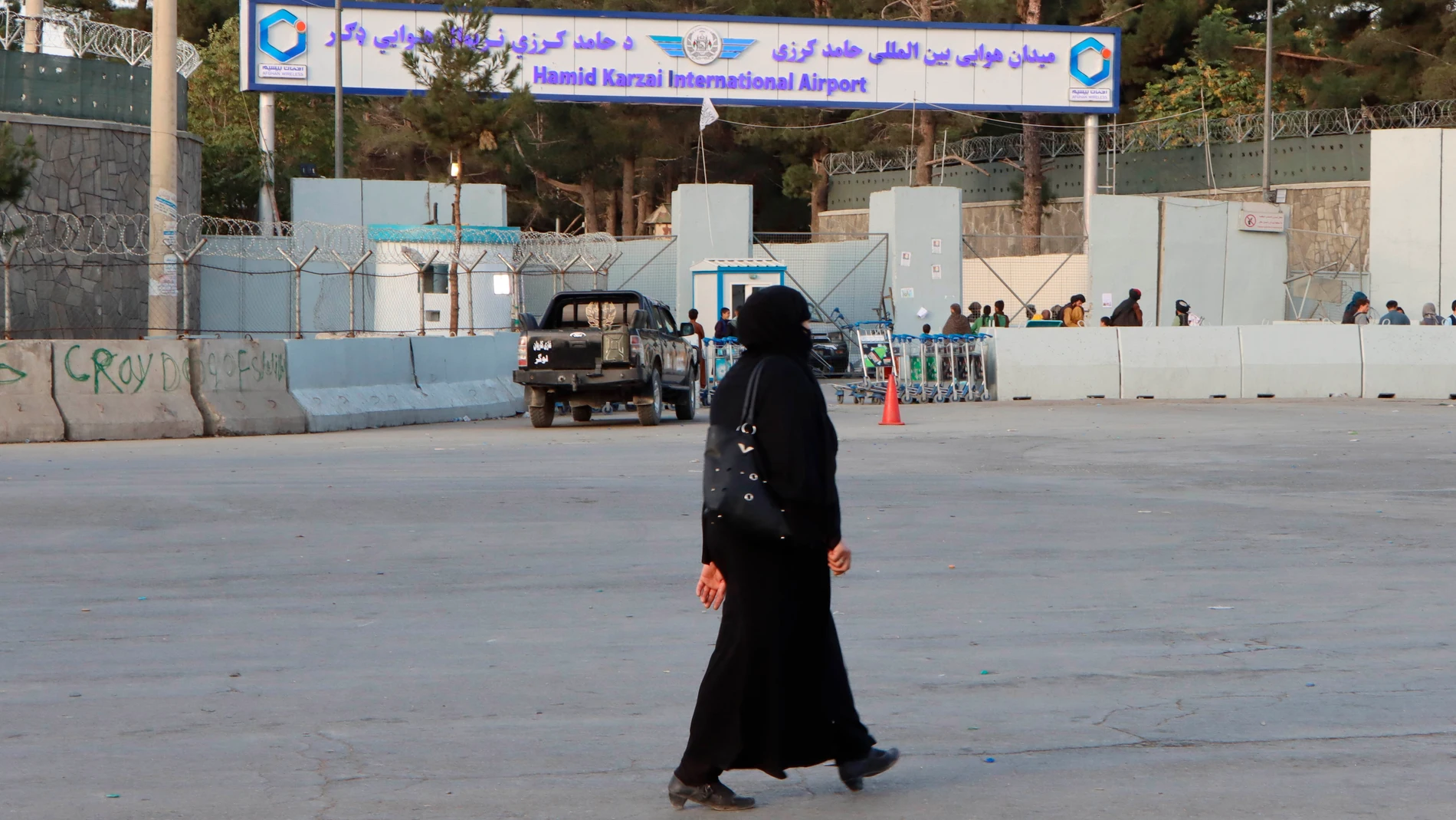 En la imagen una mujer pasa frente a la puerta del aeropuerto internacional Hamid Karzai en Kabul (Afganistán)