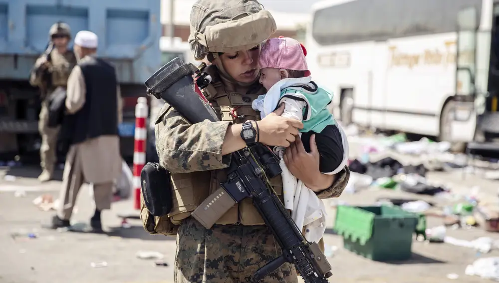 Un soldado calma a un niño afgano cerca del aeropuerto