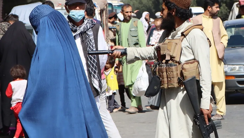 Un talibán apunta a la espalda de una mujer con burka en los alrededores del aeropuerto de Kabul la semana pasada