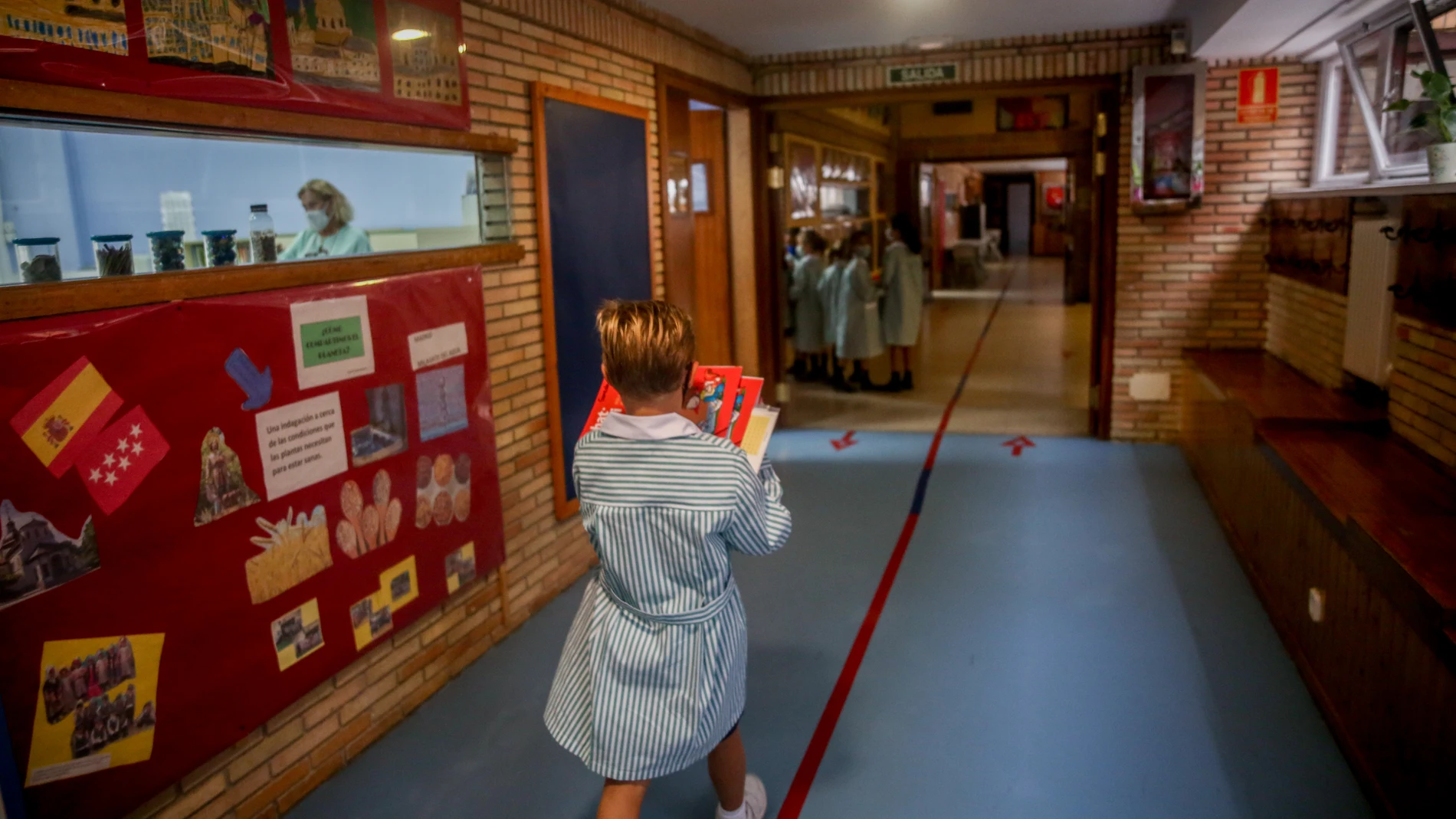 Un niño camina con libros por el hall del colegio Virgen de Europa durante el primer día de clase del curso