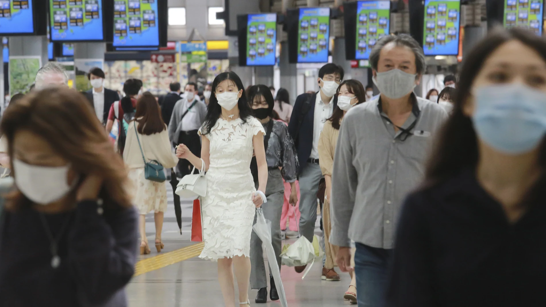 Personas con mascarilla caminan por la estación de tren en Tokio