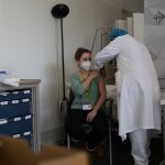 Una joven es vacunada por un trabajador sanitario