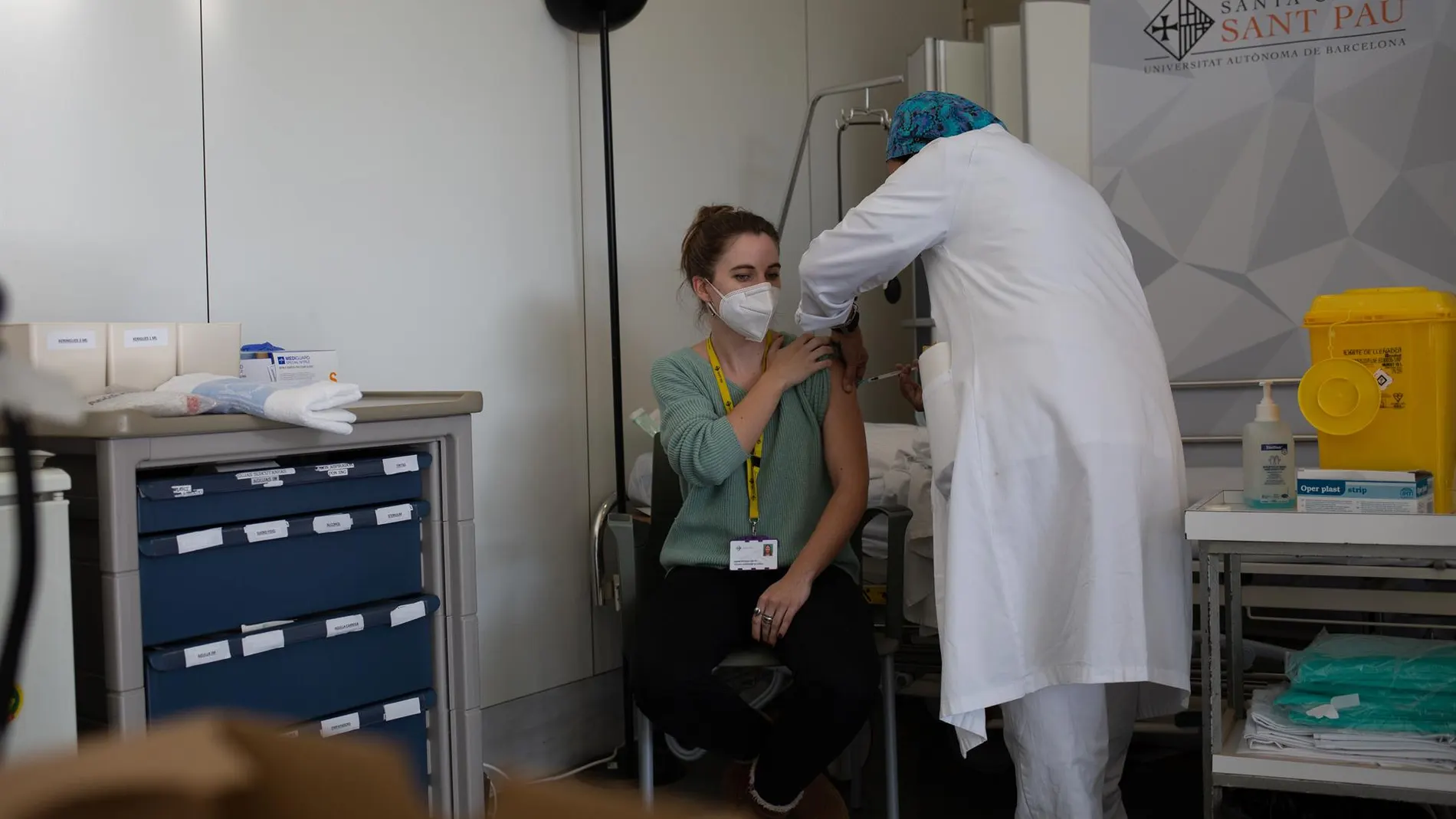 Una joven es vacunada por un trabajador sanitario