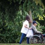Una mujer pasea con un hombre en silla de ruedas junto a una residencia en San Sebastián