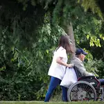 Una mujer pasea con un hombre en silla de ruedas junto a una residencia en San Sebastián