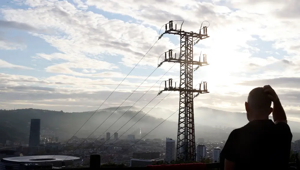 Una persona observa el cableado con el que red eléctrica transporta la energía sobre la ciudad de Bilbao | Fuente: EFE/LUIS TEJIDO