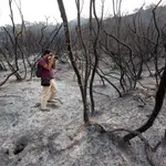 Un fotógrafo toma imágenes de una zona quemada por el incendio forestal en la Sierra Bermeja, en Málaga