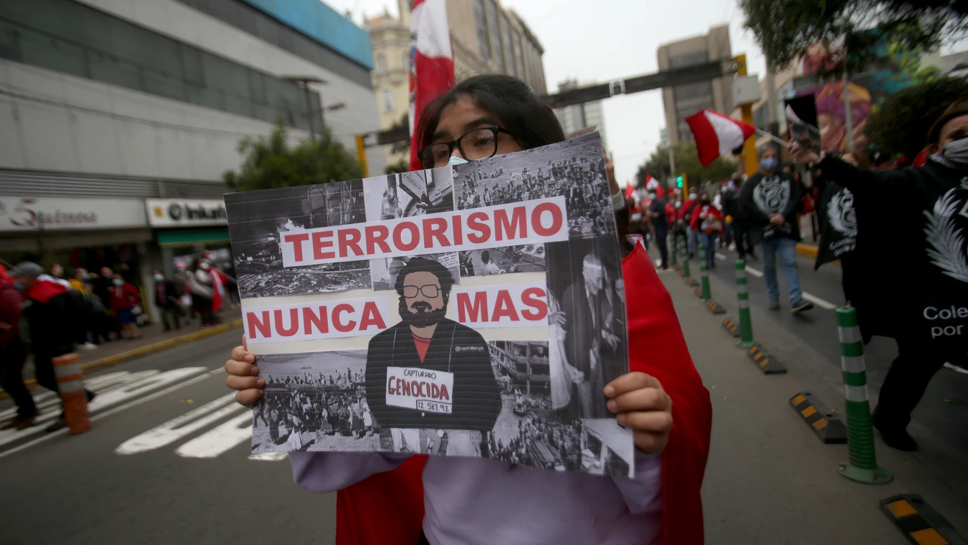 12 September 2021, Peru, Lima: A woman carries a placard describing Peruvian guerrilla leader Guzman as a mass murderer at a demonstration marking his death. Abimael Guzman, the former leader of the Peruvian guerrilla organization Shining Path (Sendero Luminoso), died at the age of 86 in a maximum-security prison, the prison administration announced on Saturday. Almost 70,000 people were killed in clashes between the Sendero Luminoso and state security forces between 1980 and 2000. Photo: Cesar Lanfranco/dpa12/09/2021 ONLY FOR USE IN SPAIN