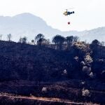 Un helicóptero trabaja en las zonas quemadas por el incendio de Sierra Bermeja (Málaga)