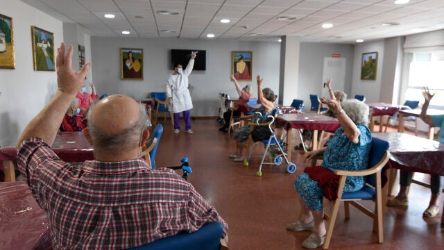 Varias personas practican ejercicios de movilidad en una sala común de la residencia de mayores sevillana "Guadaíra"
