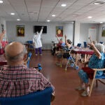 Varias personas practican ejercicios de movilidad en una sala común de la residencia de mayores sevillana "Guadaíra"