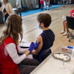 Una voluntaria de Cruz Roja administra una dosis de la vacuna a un estudiante universitario en el campus de Ciudad Universitaria de Madrid