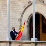 Un ujier se lleva la bandera española de la Galería Gótica del Palau de la Generalitat tras la comparecencia del presidente del Gobierno, Pedro Sánchez, después de la mesa de diálogo sobre Cataluña.