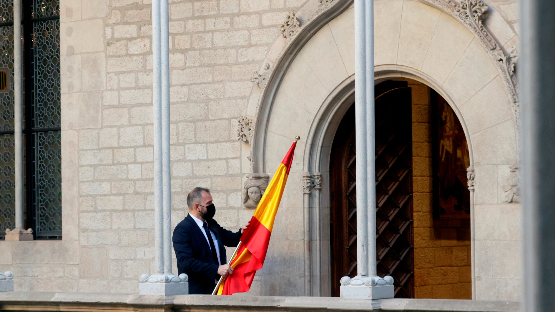 Un ujier se lleva la bandera española de la Galería Gótica del Palau de la Generalitat tras la comparecencia del presidente del Gobierno, Pedro Sánchez, después de la mesa de diálogo sobre Cataluña.