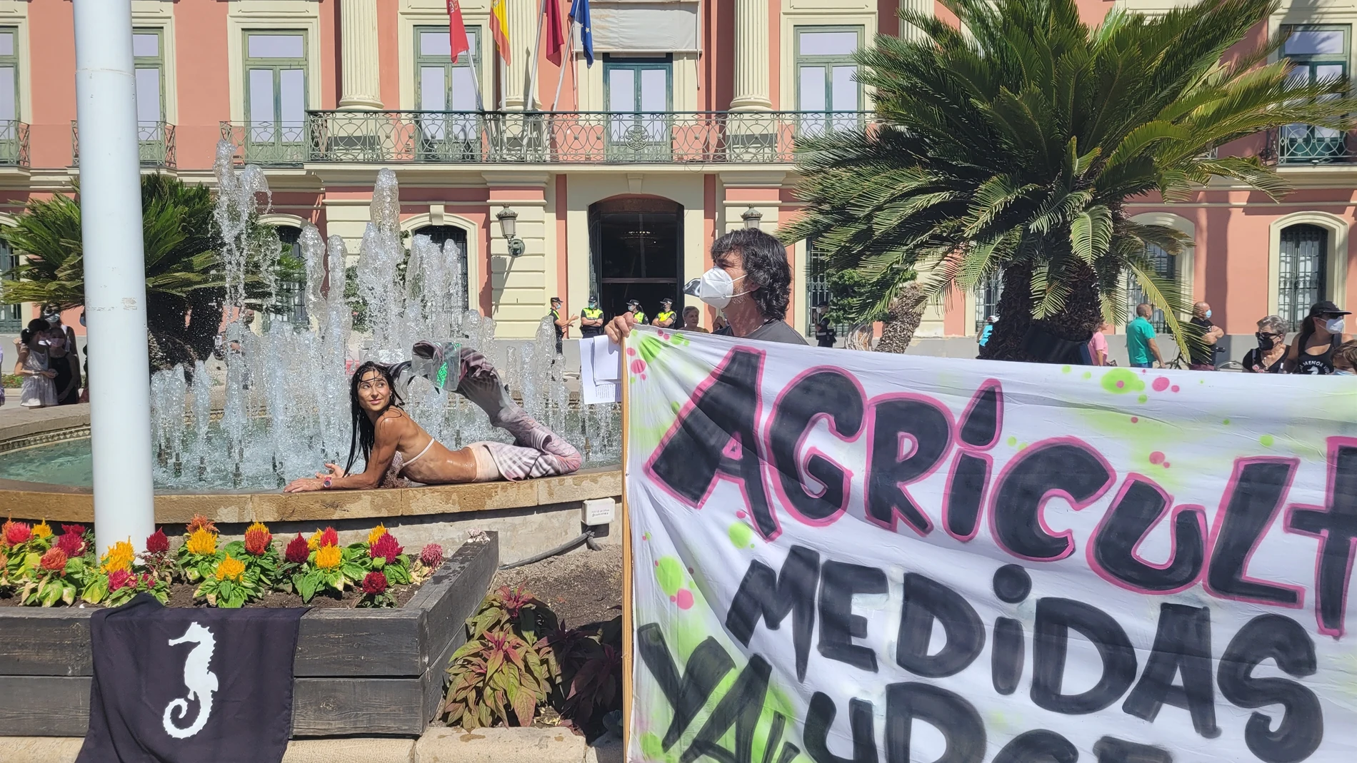 Una joven ataviada con un disfraz de sirena se moja por el Mar Menor en la céntrica plaza de La Glorieta de Murcia