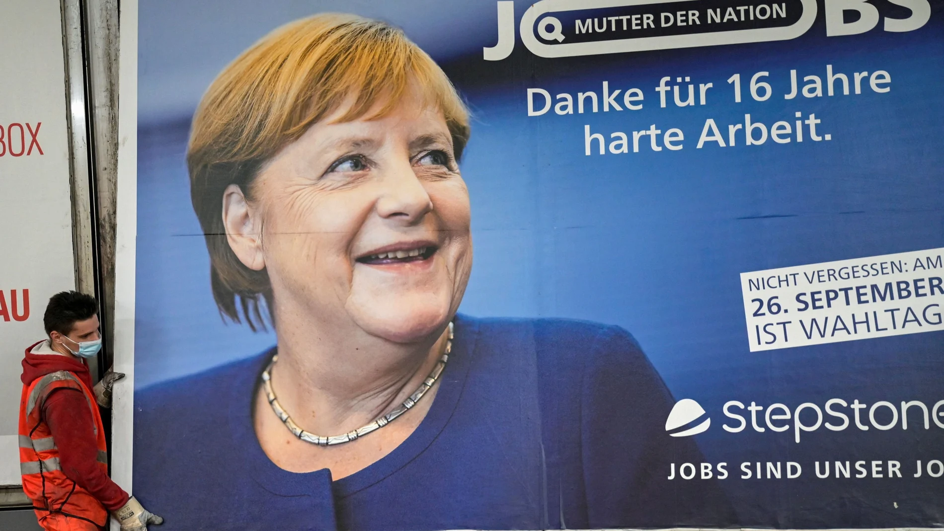 Un operario retira un cartel con la imagen de Angela Merkel