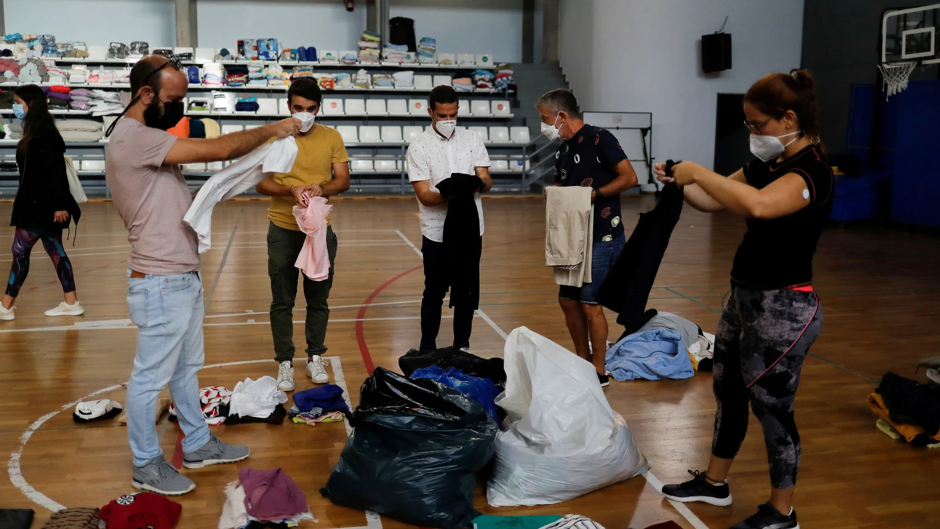 Unos voluntarios clasifican la ropa donada