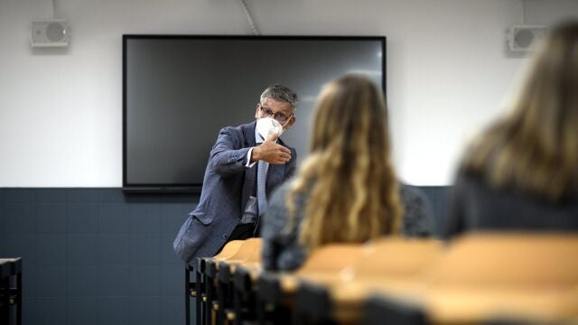 Un profesor da clase con mascarilla.