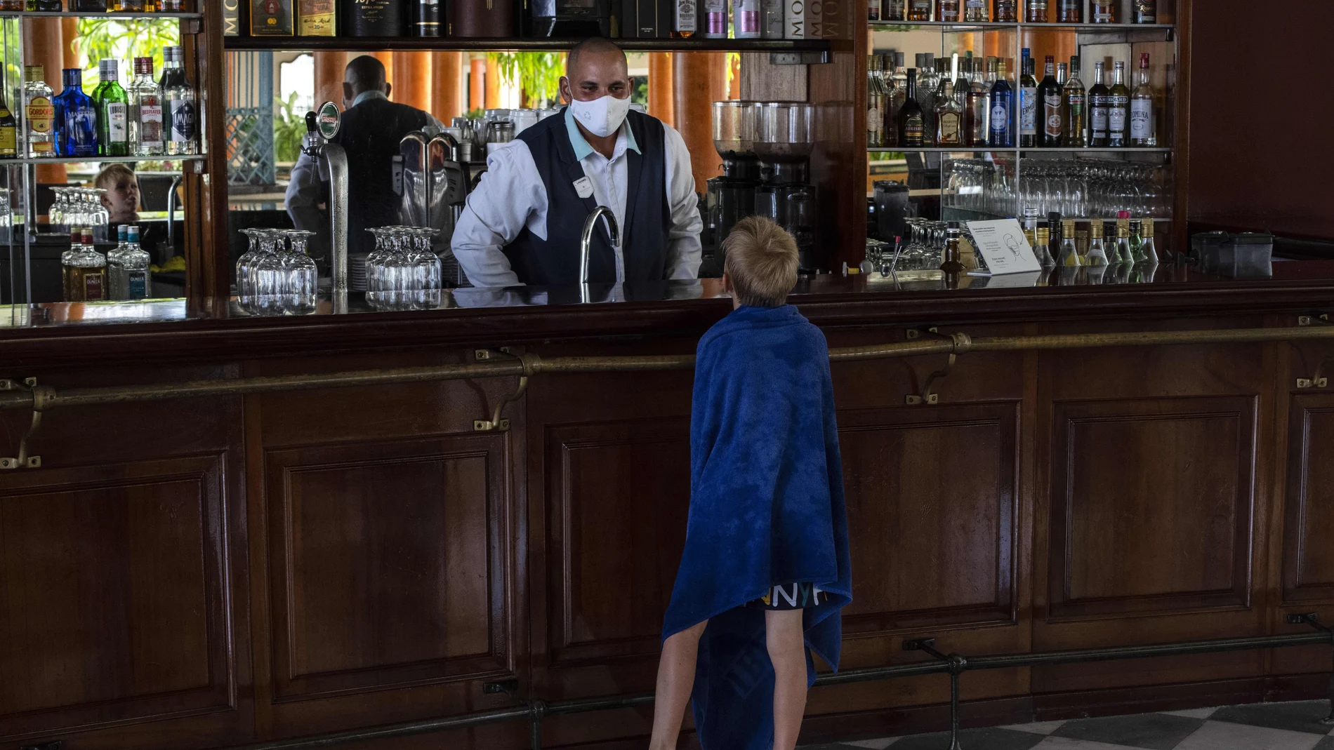 A young tourist asks a waiter for a soft drink at the Iberostar Selection Varadero hotel in Varadero, Cuba, Wednesday, Sept. 29, 2021. Authorities in Cuba have begun to relax COVID restrictions in several cities like Havana and Varadero. (AP Photo/Ramon Espinosa)