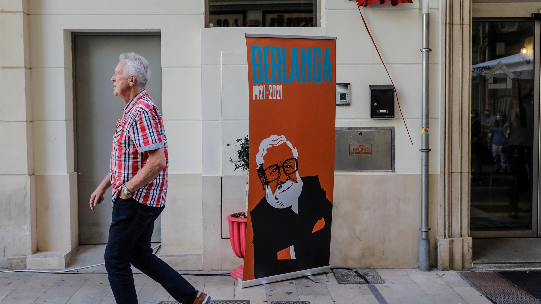 Un hombre camina frente a un 'roll-up' y una placa-homenaje a homenaje a Luis García Berlanga, aún sin descubrir, con motivo del Día del Cine Español06/10/2021