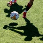 Proyección de la sombra de dos jugadores sobre el césped del terreno de juego de las instalaciones de Tajonar