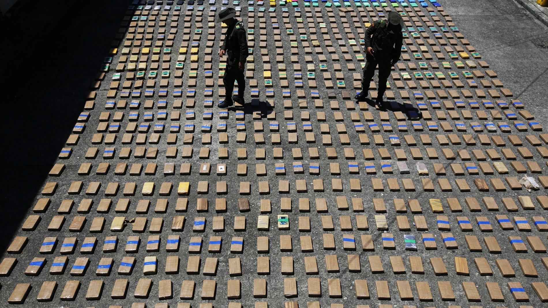 FILE - In this Thursday, Aug. 10, 2017 file photo, police officers walk among packages of seized cocaine at the Pacific port of Buenaventura, Colombia, after about one ton of cocaine was seized in a container during an operation by counternarcotics police at the port. In 2018, Capt. Juan Pablo Mosquera, a Colombian national police officer who was part of an elite unit that worked closely with U.S. anti-narcotics agents, was extradited to Miami to stand trial on charges he betrayed the U.S. Drug Enforcement Administration to the same traffickers they were jointly fighting. (AP Photo/Fernando Vergara)