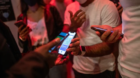 Una persona muestra un código QR para entrar a un local de ocio nocturno